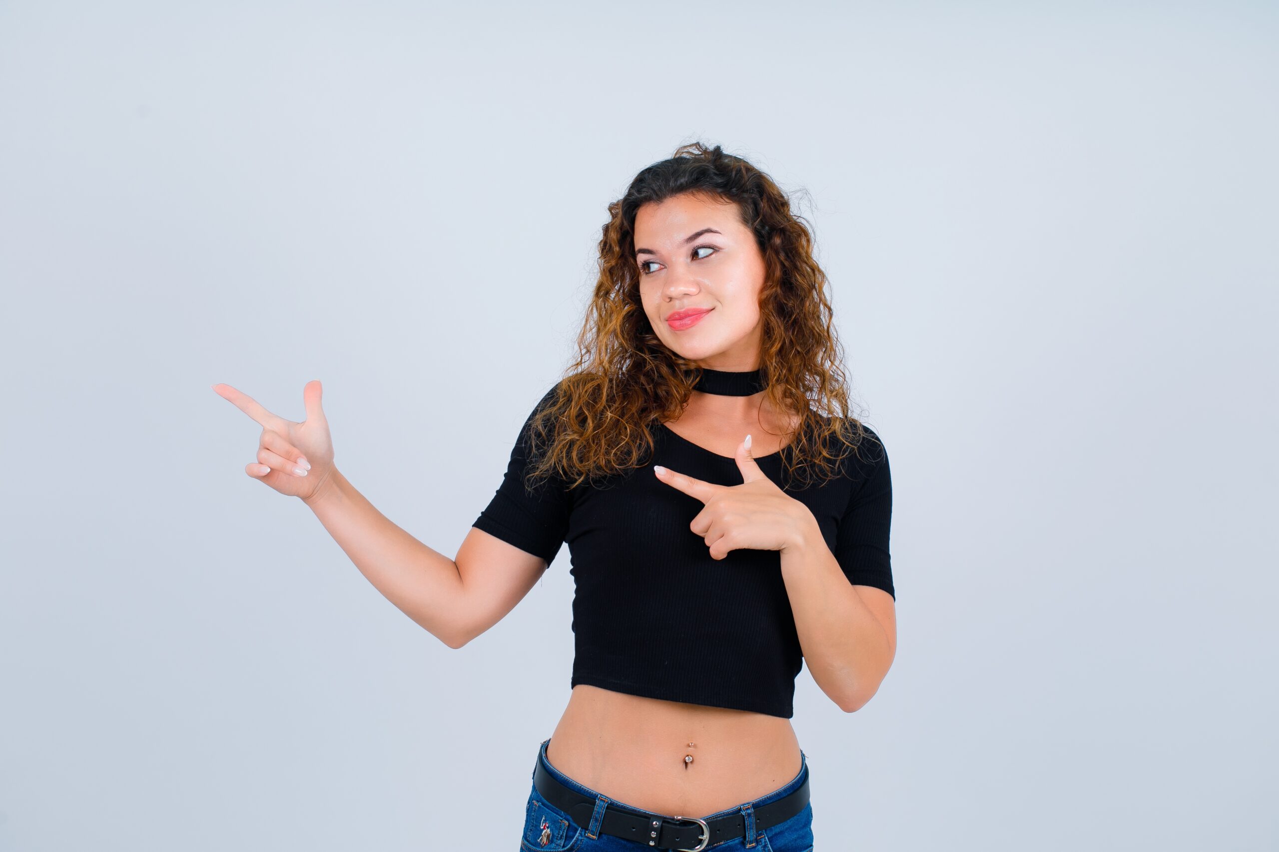smiling girl is looking left by pointing left with forefingers white background